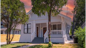 A two-story house with a front porch, a staircase leading to the entrance, and a small front yard.