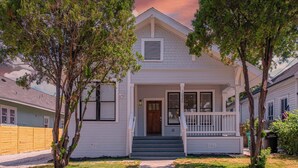 A two-story house with a front porch, a wooden fence, and a driveway.