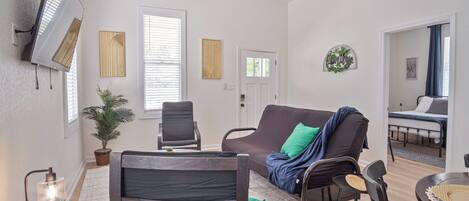 A living room with a sofa, chairs, a TV, and a ceiling fan.
