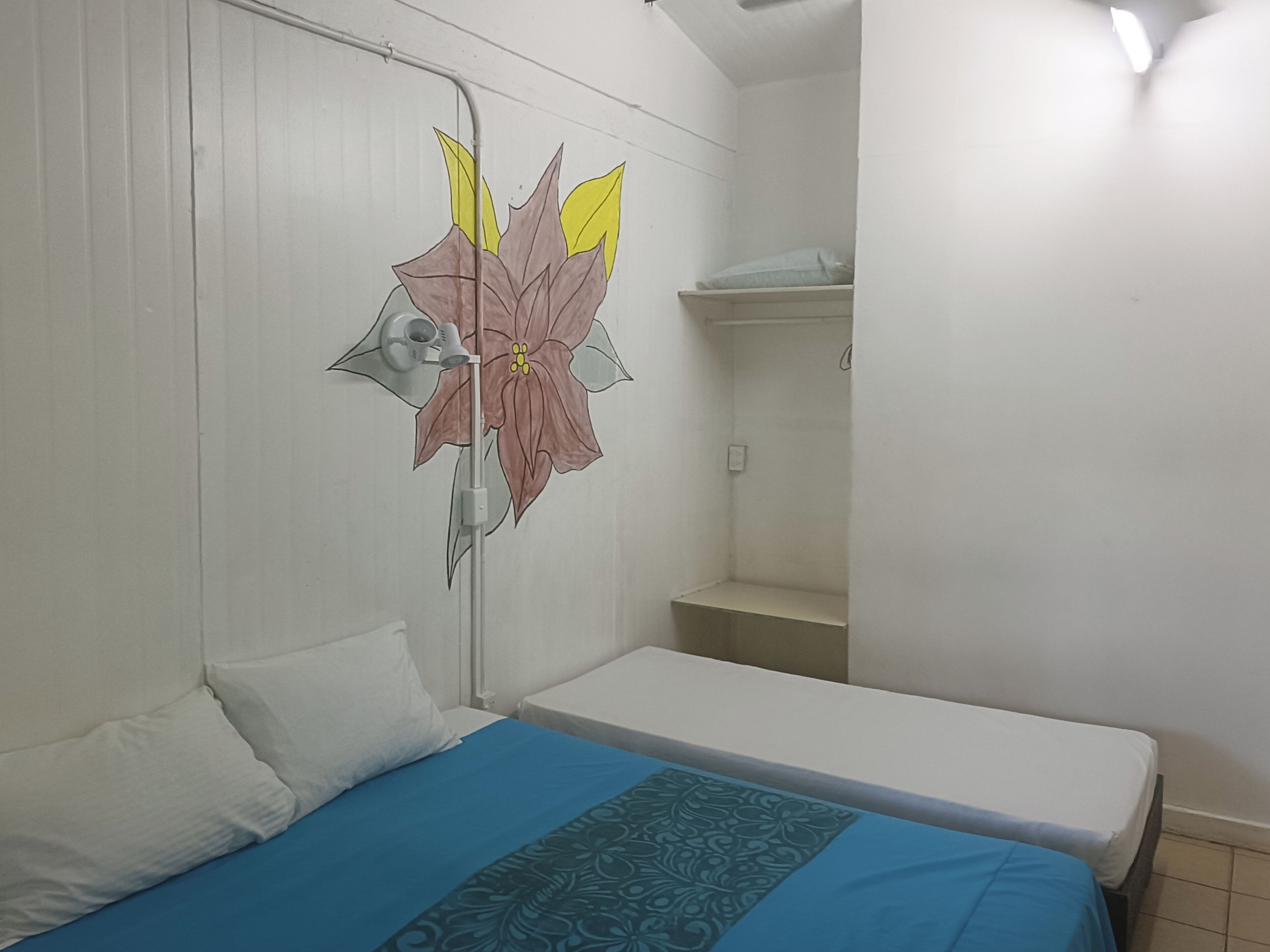 A room with a bed, a wall-mounted radiator, and a shelf.