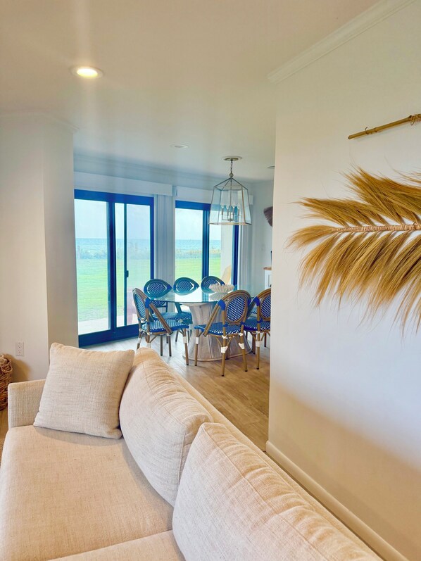 A modern living room with a sofa, dining table, chairs, and a view of the outdoors.