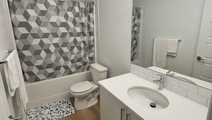 A modern bathroom with a shower, toilet, sink, and a mirror. - Chezeey’s Home - Refresh, Relax, Work & Unwind - new beautiful basement suite (Edmonton)