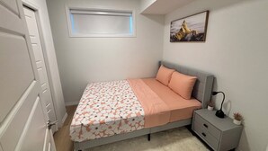 A bedroom with a bed, a nightstand, a window with blinds, a ceiling light, and a wall-mounted picture. - Chezeey’s Home - Refresh, Relax, Work & Unwind - new beautiful basement suite (Edmonton)