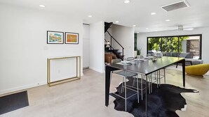 Et moderne spiseområde med et centralt bord, stole og en måtte i sort-hvid kvæderust.