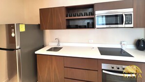 A compact kitchen with a refrigerator, microwave, sink, and oven. - Peregrina Tulum 302B 1BR Condo (Tulum)