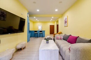 A living room with a sofa, a coffee table, and a TV. There is a kitchen area in the background. - Luxurious Xinyi 101/City Hall MRT - Excellent location (Taipei City)