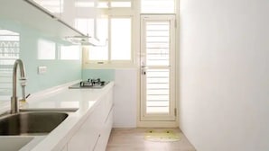 A compact kitchen with white cabinets, a stainless steel sink, and a small window.