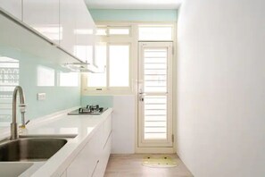 A compact kitchen with white cabinets, a stainless steel sink, and a small window. - Luxurious Xinyi 101/City Hall MRT - Excellent location (Taipei City)