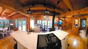 A wooden cabin interior with a kitchen, dining area, and living room.