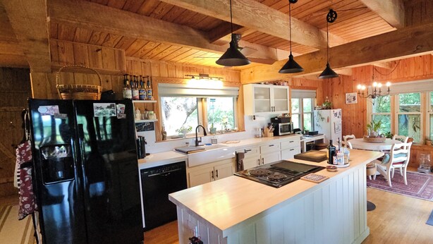 A wooden cabin kitchen with a central island, built-in appliances, and pendant lighting.