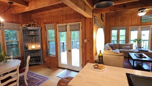A wooden cabin interior with a dining area, a sofa, and a coffee table.