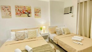 Una habitación de hotel con dos camas, una mesita de noche con lámpara y decoración en la pared.