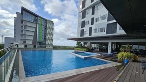 Una piscina en la azotea con terraza de madera, rodeada de edificios modernos.