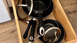 Een keukulaag met een zwarte koekenpan, een steelpan en een pan.