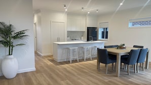 Una cocina moderna con armarios blancos, un refrigerador negro y una isla central con taburetes de bar.