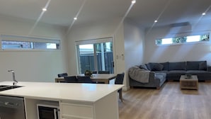 Una cocina moderna con lavavajillas y microondas integrados, un comedor con mesa y sillas, y una sala de estar con sofá y mesita de centro.