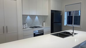 Una cocina moderna con armarios blancos, un refrigerador negro, una estufa a gas y una ventana con vistas al exterior.