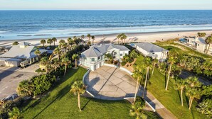 A coastal residential area with houses, a beach, and a clear sky.