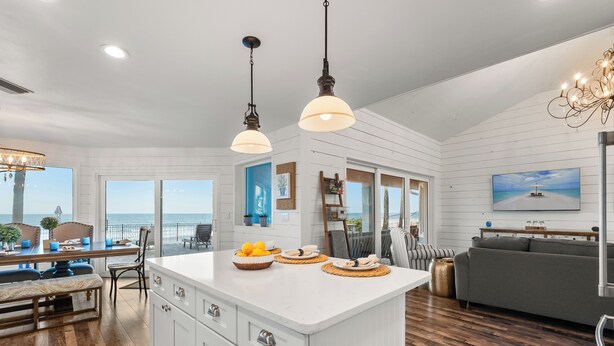 A spacious kitchen with a large island, white cabinetry, and a view of the ocean.