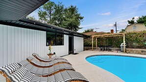 Une piscine avec des chaises longues et une pergola.