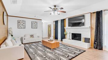 TV connectée, cheminée, livres, chaîne hi-fi