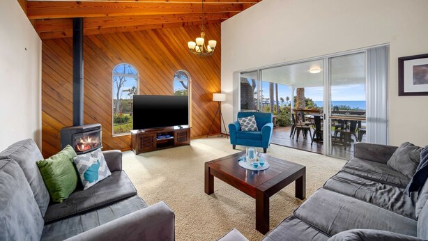 A spacious living room with a fireplace, a flat-screen TV, and a balcony with a view.