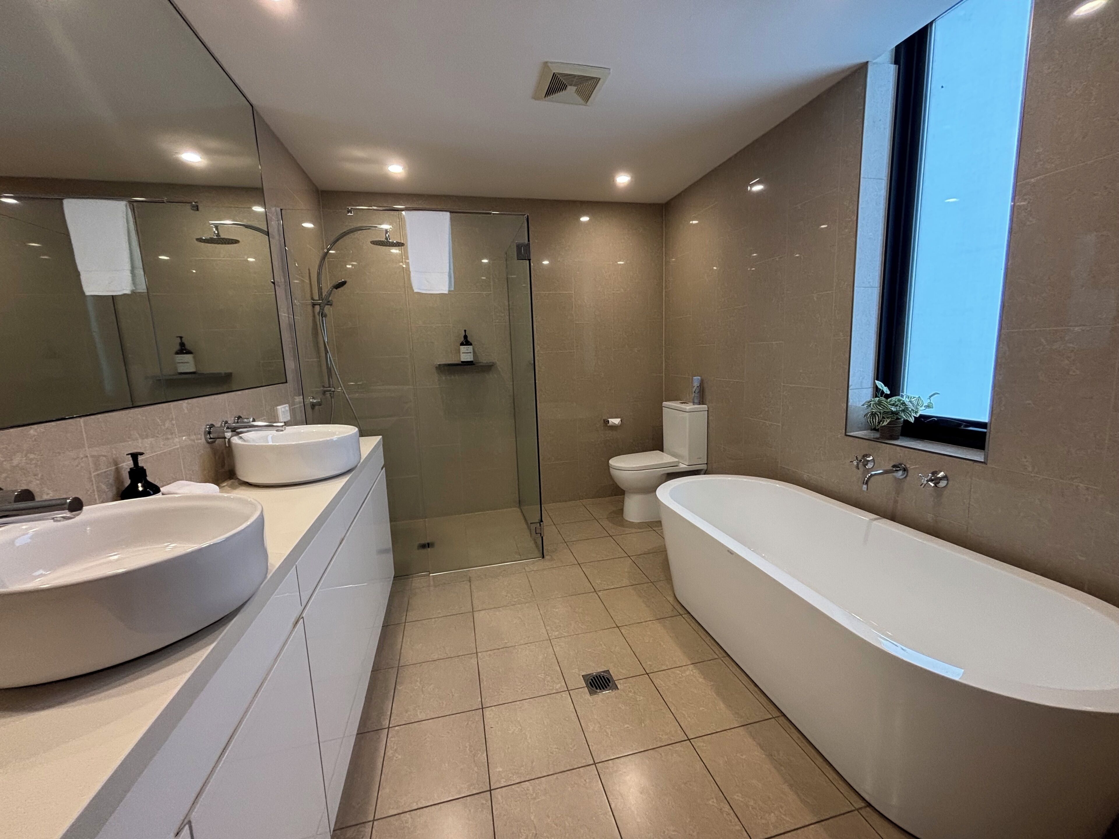 Une salle de bain moderne avec une douche à parois de verre, une baignoire sur pieds et deux vasques.
