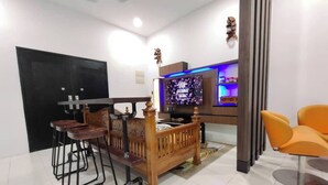 A modern living room with a TV, wooden furniture, and a small seating area. - Nur Hartamas Homestayportdickson (Port Dickson)