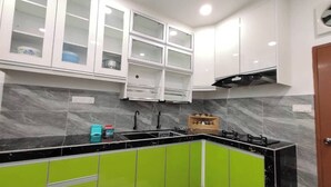 A kitchen with white cabinets, a black countertop, and green lower cabinets. - Nur Hartamas Homestayportdickson (Port Dickson)