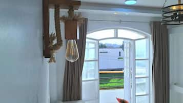 A room with a large window, a hanging light fixture, and curtains.