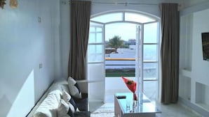 A living room with a sofa, a glass coffee table, and a view through a large window. - Superb 1-bedroom apartment #10 (Luxor Governorate)