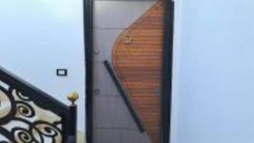 A modern building entrance with a wooden door and a black metal staircase.