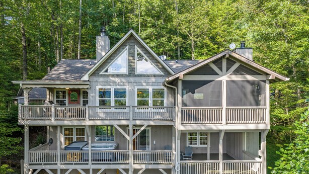 A two-story wooden house with a balcony on the upper level, surrounded by trees. - Mountain Views, Hot Tub & Resort Amenities in Sapphire, NC (Sapphire)