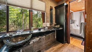 Ein modernes Badezimmer mit großem Fenster, einem schwarzen Schrank und Holzboden.