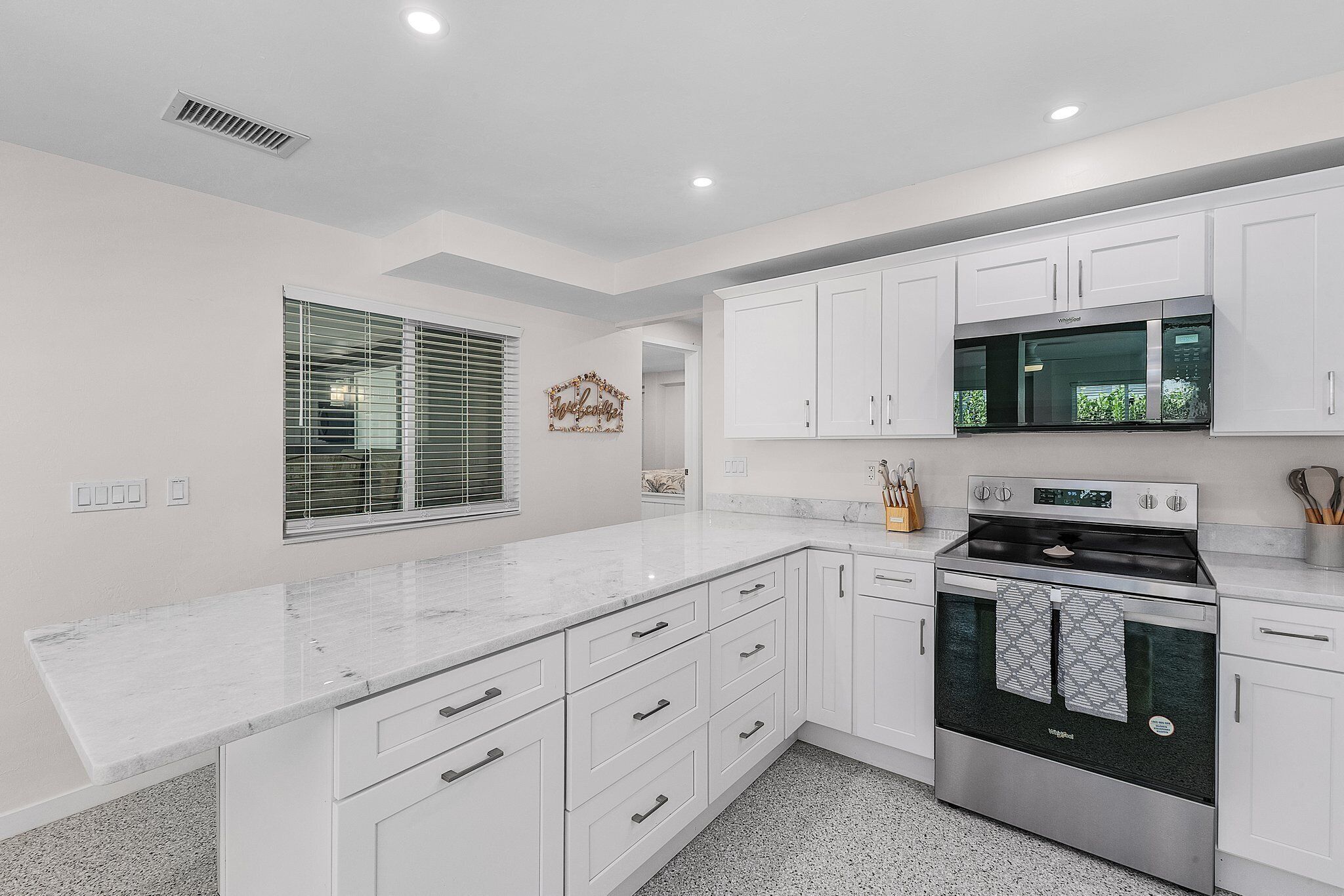 A modern kitchen with white cabinetry, a stainless steel oven, and a marble countertop.