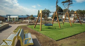 Un parque infantil con columpios y un banco.