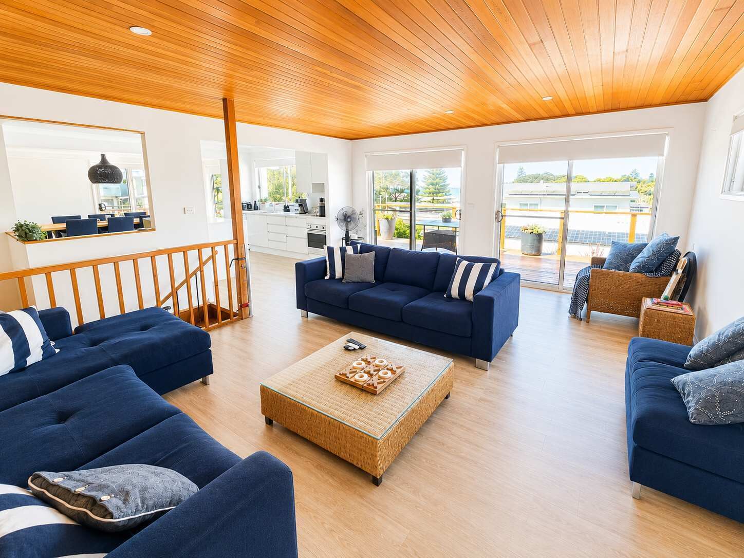 Una sala moderna con techo de madera, un amplio sofá, una mesa de centro y vistas al exterior a través de grandes ventanales.