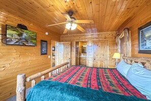 A wooden cabin interior with a bed, a ceiling fan, a television, and a framed picture on the wall. - On Eagles Wings・Panoramic Views・Hot Tub・Game Room・Resort Access (Sevierville)