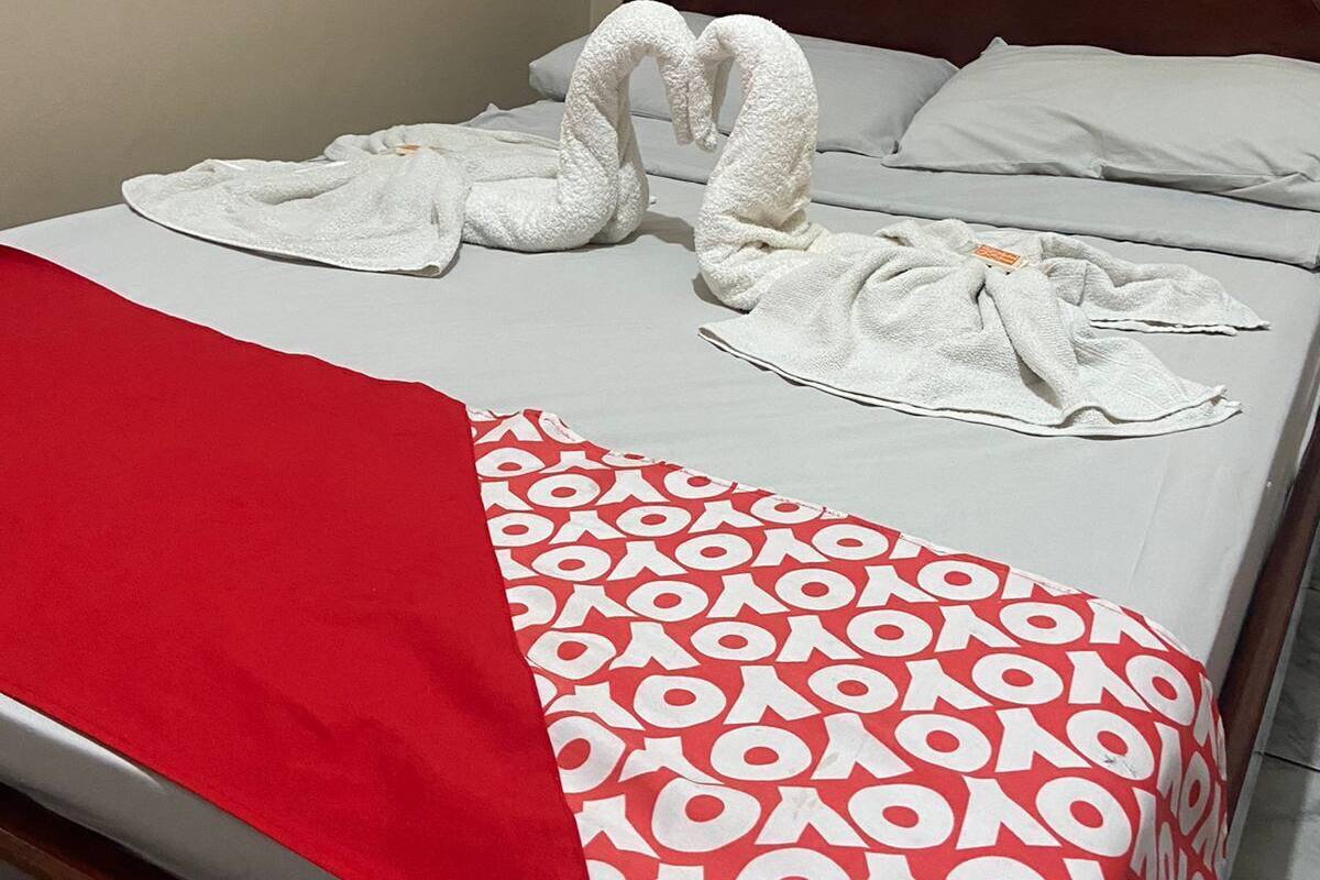 Ein Hotelzimmer mit einem Bett, einer rot-weißen Bettdecke und zwei Handtüchern, die als Schwan drapiert sind.