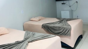 Ein Hotelzimmer mit zwei Betten, einem an der Wand montierten Flachbildfernseher und einer Klimaanlage.