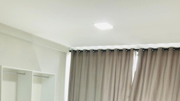 Ein Zimmer mit zwei Betten, einem weißen Regal und einem Fenster mit Vorhängen.