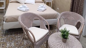 A bedroom with a large bed, two bedside tables, a wall-mounted artwork, and a patterned floor. - Anninedda rooms (Palermo)