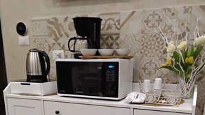 A white kitchen counter with a microwave, kettle, and a small white cabinet with drawers. - Anninedda rooms (Palermo)