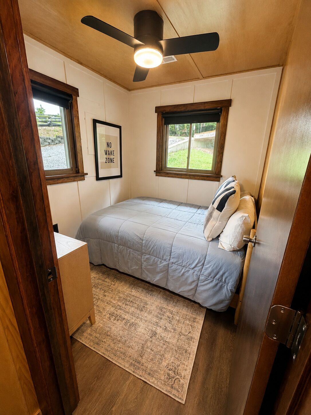 A bedroom with a bed, a ceiling fan, a window, and a rug.