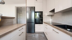 Une cuisine moderne avec des meubles blancs, un réfrigérateur en acier inoxydable et un four noir.