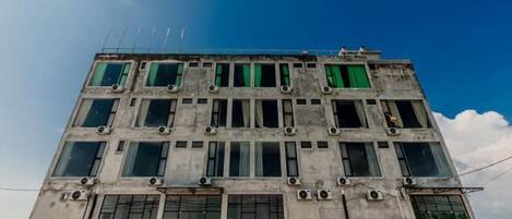 Un edificio de varios pisos con fachada de concreto, ventanas amplias y unidades de aire acondicionado visibles.