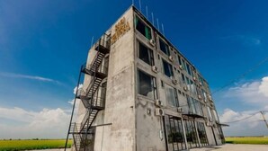 Ένα σύγχρονο κτίριο με πρόσοψη από οπλισμένο σκυρόδεμα, μεγάλα παράθυρα και μια κεντρική σκάλα.