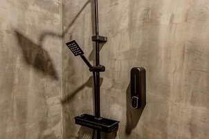 A shower with a handheld showerhead and a wall-mounted control panel.