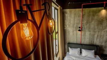 A room with a bed, curtains, and two hanging light fixtures.