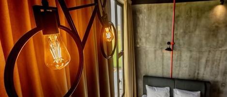 A room with a bed, curtains, and two hanging light fixtures.